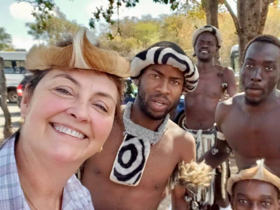 An Adventures for Solo Travelers guest smiles with local performers during a cultural experience in Zimbabwe on a guided small group Africa adventure for travelers age 45+.