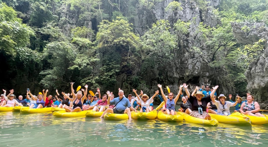 AFS travelers waving from yellow kayaks beneath limestone cliffs